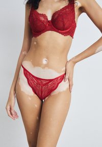Rød blonde bh og trusse sæt, der har indviklede blomster mønstre, bølgede kanter og blød mesh, der fremhæver den livlige farve og delikate design.