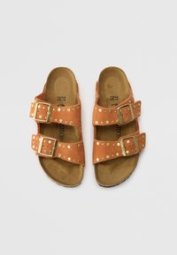 Sandali in suede marrone con due fibbie regolabili, borchie color oro lungo le cinghie e una soletta testurizzata.
