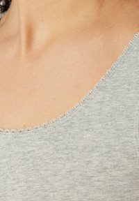Szara bluzka z dekoltem w kształcie łódki, ozdobiona delikatnym białym koronkowym wykończeniem, wykonana z miękkiego, teksturowanego materiału w melanżowy wzór.