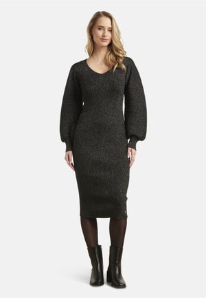 Black ribbed knit dress with a fitted silhouette, deep V-neck, and puffed long sleeves. Worn with black heeled ankle boots.