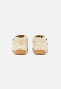 Lichtbeige kinderschoenen met een zachte gestructureerde bovenkant, ronde achterkant en klittenbandsluiting. Rubberen zool met subtiele stikdetails.
