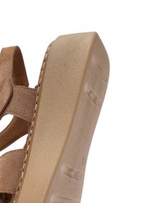 Sandalo wedge in suede marrone con suola beige testurizzata, design aperto e cuciture dettagliate lungo i bordi.