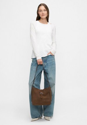 Brown suede handbag with a buckle detail, paired with a white long-sleeve top and light blue high-waisted jeans. Simple, casual design.