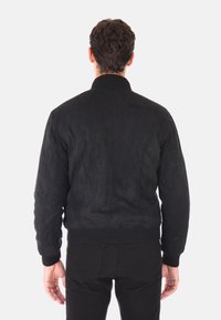 Giacca bomber in suede nero con colletto e polsini a coste. Presenta una superficie liscia e un design leggermente accorciato. Vista posteriore, senza decorazioni.