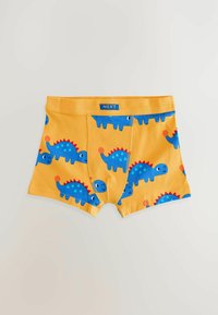 Žluté dětské boxerky s modrými ilustracemi dinosaurů a červenými ostny, značené malou modrou nálepkou Next na pasu.