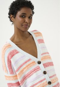 Cardigan rayé aux couleurs pastel comme le bleu, l'orange et le rouge, avec un col en V profond et des boutons marron sur le devant.