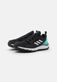 Zapatillas deportivas negras con parte superior de malla, rayas laterales blancas y un acento en azul claro en el talón. Suela gruesa blanca y negra con agarre texturizado.