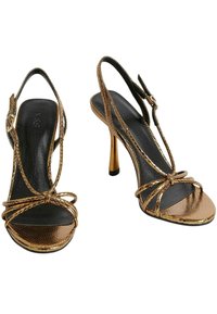 Złote obcasy w stylu slingback, z krzyżującymi się paskami i teksturowanym wierzchem. Czarne wkładki i cienki złoty obcas typu stiletto.