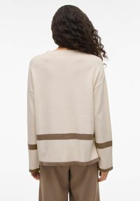 Pull beige à rayures horizontales marron, tricot texturé, col rond, épaules tombantes et coupe décontractée. Tissu doux, style décontracté.