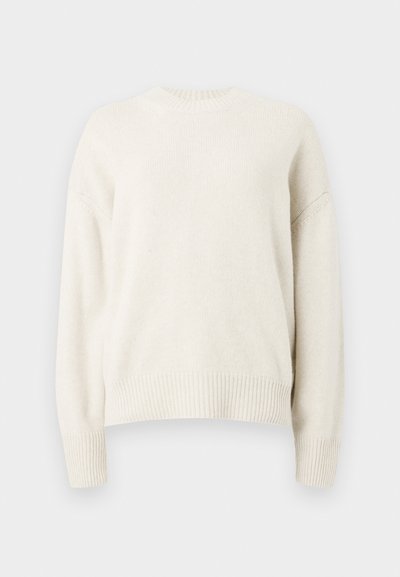 Teksturirana krema pulover s rebrastim okovom in manšetami. Ima sproščen kroj in malo spuščena ramena. Brez vidnih vzorcev.