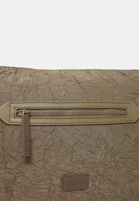 Borsa in tessuto marrone dalla texture arricciata, con bordo in pelle beige e cerniera. Presenta una piccola etichetta con il logo del marchio nella parte inferiore.