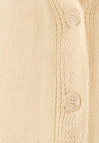 Knitted beige cardigan featuring textured fabric and a row of three cream buttons along the front placket.
