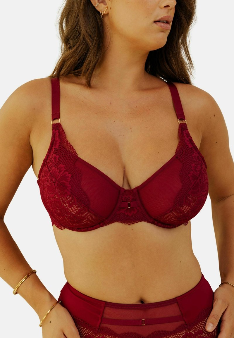Soutien-gorge en dentelle bourgogne avec panneaux transparents, motif floral, soutien-gorge à armatures, bretelles réglables et accents en métal doré.