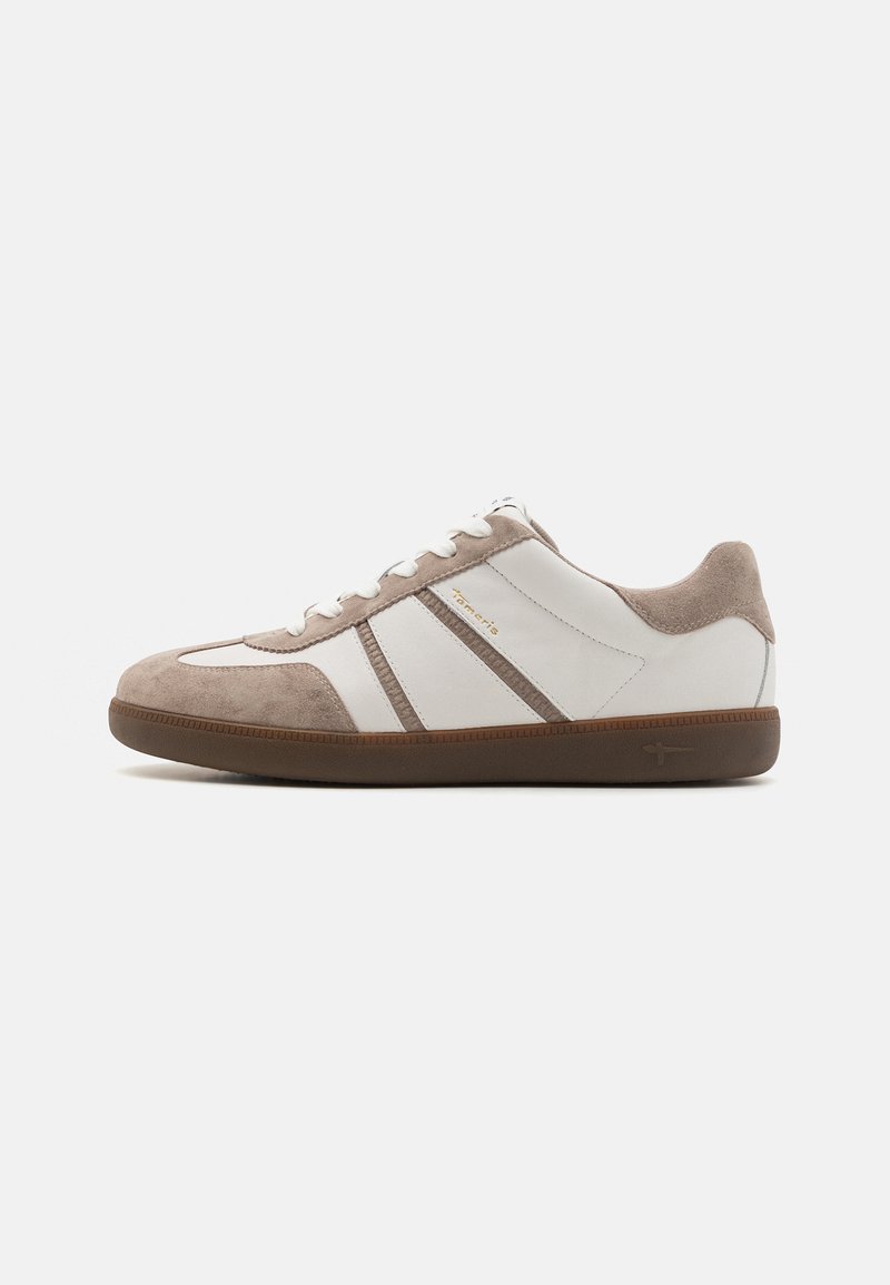 Chaussure de sport blanche et beige en suède et caoutchouc ; présente un devant lacé, des bords texturés et une semelle en caoutchouc marron.