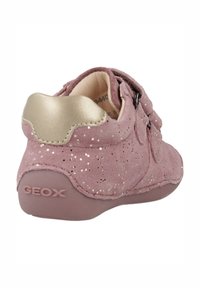 Scarpa in suede rosa con dettagli dorati, chiusure a doppia cinghia e punta rotonda. La suola è di un rosa chiaro con "GEOX" impresso.