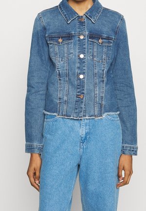 Kurtka dżinsowa w średnim odcieniu z krótkim krojem, dwoma przednimi kieszeniami i miedzianymi guzikami. Postrzępiony dół i kołnierz. Długie rękawy.