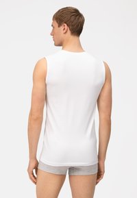 Witte mouwloze shirt gemaakt van zachte stof, ontworpen met een ronde halslijn, een getailleerde pasvorm en een gladde textuur. Van achteren gezien.
