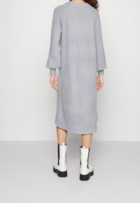 Robe en tricot côtelé grise avec de longues manches bouffantes et une coupe décontractée. Assortie à des bottines blanches avec des accents latéraux noirs.
