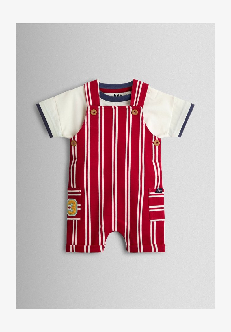 Peto de niño pequeño a rayas rojas y blancas con botones de madera y bolsillo parche, superpuesto a una camiseta blanca de manga corta con ribete azul marino.