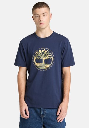 Granatowy, bawełniany T-shirt z logo złotego drzewa i tekstem w okręgu, krótkie rękawy i luźny krój. Prosty, nieozdobiony design.