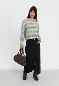 Lys grøn stribet sweater, høj talje sort denim nederdel med slids foran, sorte ankelstøvler og en olivengrøn håndtaske.