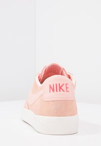 Nike-sneakers i ljusrosa mocka med en vit gummisula. Har en framträdande rosa logotyp på hälen och en slät inredning.