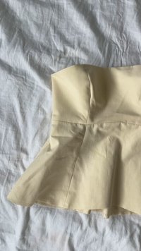 Top bustier di colore giallo chiaro, aderente, con orlo svasato. Tessuto leggero e morbido con cuciture minime e silhouette strutturata.