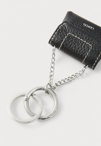 Black textured leather wallet with white stitching, featuring a silver chain and two interlinked silver rings. Notable brand logo present.