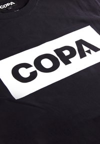 Zwarte katoenen t-shirt met een grote witte rechthoekige graphic met het woord "COPA" in vetgedrukte zwarte letters, met een gladde textuur.