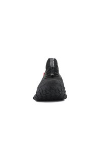 Chaussure de sport noire avec une semelle en caoutchouc texturée, des lacets élastiques et une languette de traction. Dispose d'un design minimaliste et d'une tige en tissu respirant.