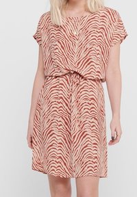 Vestido de manga corta con cintura ajustable, hecho de una tela ligera con un patrón de rayas de cebra en beige y óxido. Textura suave.