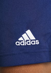 Navy modré športové šortky s bielym vyšitým logom Adidas, vyrobené z hladkej tkaniny s čistým prešívaním pozdĺž lemu.