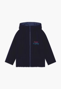 Námořnická sametová bunda na zip s kapucí, která má dvě přední kapsy a barevně vyšitý nápis "miluj sám sebe" na hrudi.