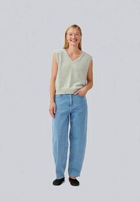 Light gray sleeveless v-neck sweater paired with loose-fit light blue jeans and black slip-on shoes. Simple design with soft texture.