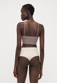 Ensemble de soutien-gorge et culotte comprenant un bralette côtelé marron clair avec des bretelles fines et une culotte taille haute beige lisse.