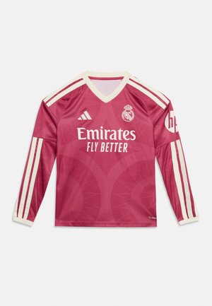 Camiseta de fútbol de manga larga del Real Madrid en rosa con rayas blancas, logo de Adidas, escudo del club y texto del patrocinador "Emirates Fly Better".