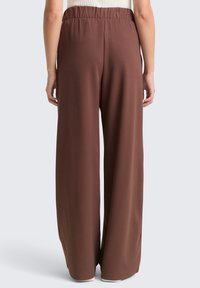 Brown wide-leg pants made from a smooth fabric. Features an elastic waistband and clean, straight-cut legs, with no visible patterns.
