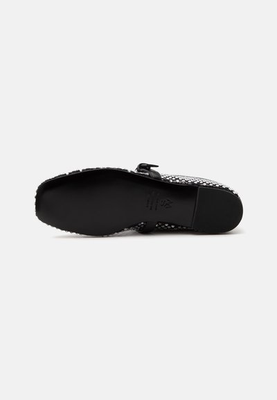 Chaussure femme à semelle noire, petit talon, bout carré et dessus décoré de clous argentés et d'une petite bride à boucle.
