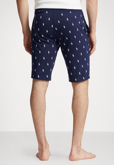 Navy shorts featuring a repeating white polo logo pattern, made of lightweight fabric, with a slim fit and elastic waistband.