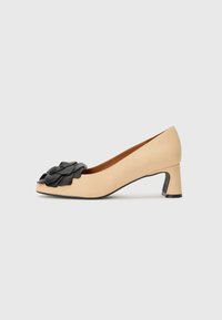 Pompe en cuir beige avec une accent floral noir, à bout carré et un talon bloc de hauteur intermédiaire. Texture lisse avec une finition mate.