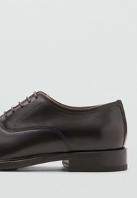 Chaussure en cuir de style habillé, couleur marron foncé, avec une finition lisse, un laçage et un bout arrondi. Talon bas empilé avec peu de détails.