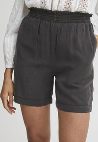 Black elastic-waist shorts with a relaxed fit, pleated texture, and rolled hems, crafted from lightweight cotton fabric.