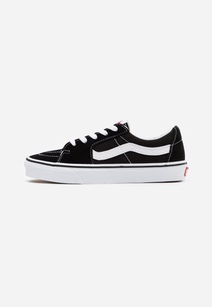 Schwarze Wildleder-Sneaker im Low-Top-Stil mit weißen Lederakzentstreifen, weißer Gummisohle und schwarzen Schnürsenkeln. Verstärkter Zehenbereich mit seitlicher Naht.