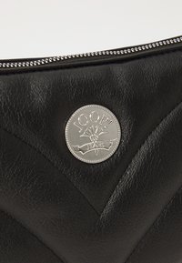 Clutch in pelle nera con un emblematico logo argento lucido e un motivo текстurizzato. La parte superiore include una zip in metallo per la chiusura.