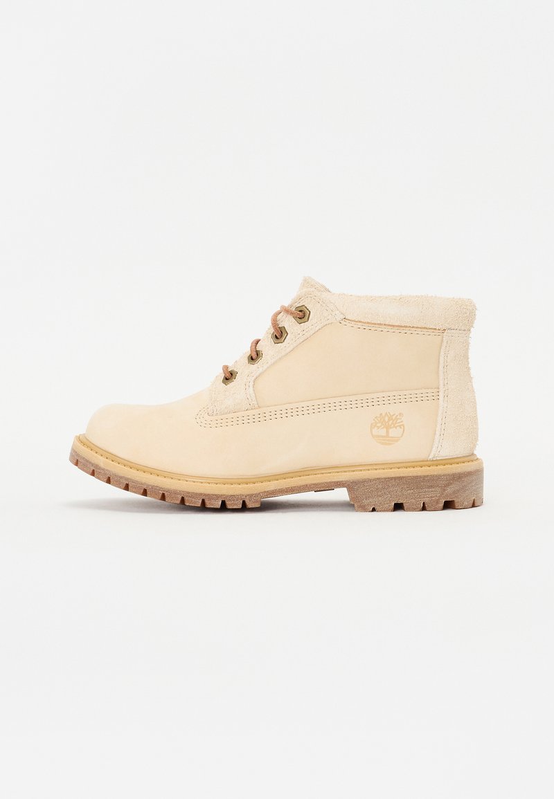 Beige leren enkelboot met een suede kraag, ronde neus, bruine veters en een dikke rubberen zool. Heeft een geperst logo aan de zijkant.