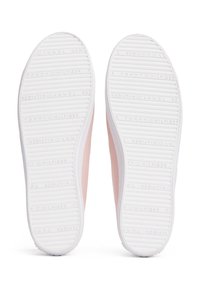 Pár světle růžových tenisek z pohledu podrážek, s bílými gumovými spodky a textem "Tommy Hilfiger" vyraženým v vzorku. 