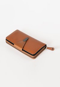 Portafoglio in pelle marrone con finitura testurizzata, zip nera e chiusura a linguetta con un accento argentato. Design compatto con dettagli di cucitura.