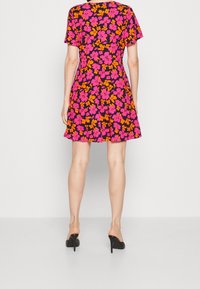 Sukienka z krótkim rękawem na ciemnym tle z żywym różowym i pomarańczowym wzorem kwiatowym. Posiada rozkloszowany dół i luźny krój.