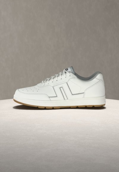 Λευκό χαμηλό sneaker με διάτρητη μύτη, λευκά κορδόνια, καουτσούκ σόλα και γκρι εσωτερική επένδυση, εμφανίζεται σε ουδέτερη επιφάνεια και φόντο.