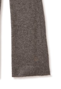 Bufanda de punto gris hecha de material suave con bordes acanalados. Tiene un pequeño detalle de logo cerca del dobladillo, que presenta un patrón sutil.